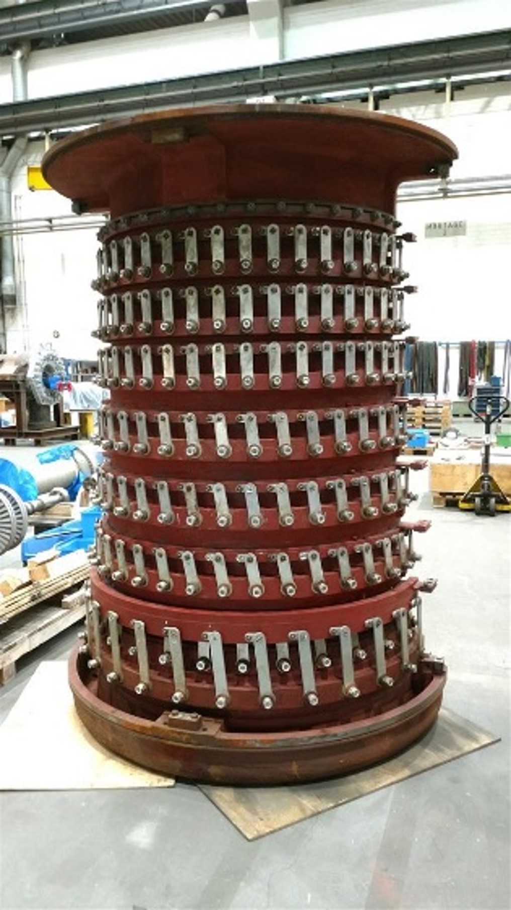  Large, curved turbine component with multiple rows of blades in a workshop environment.