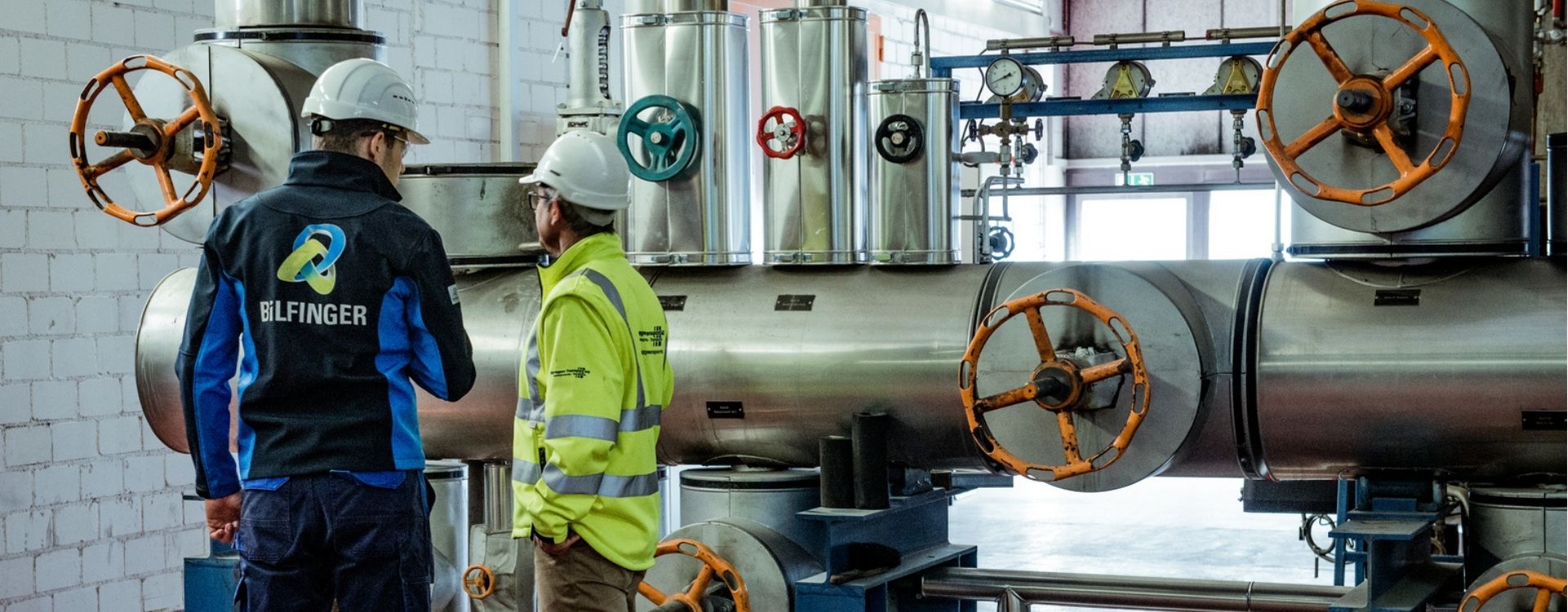 Bilfinger colleague speaking to a customer in front of an industrial installation.