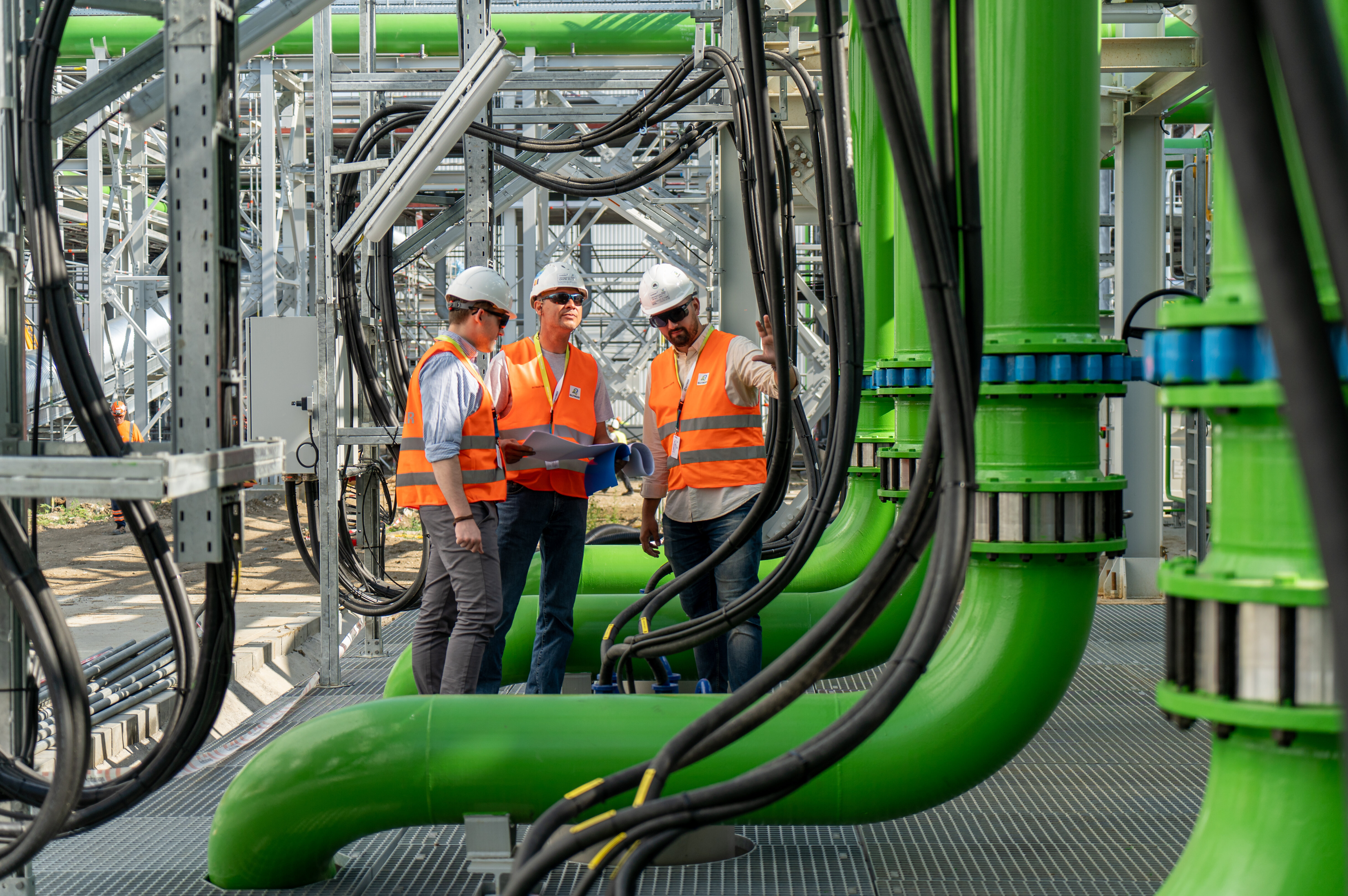 3 engineers inspecting piping and hoses