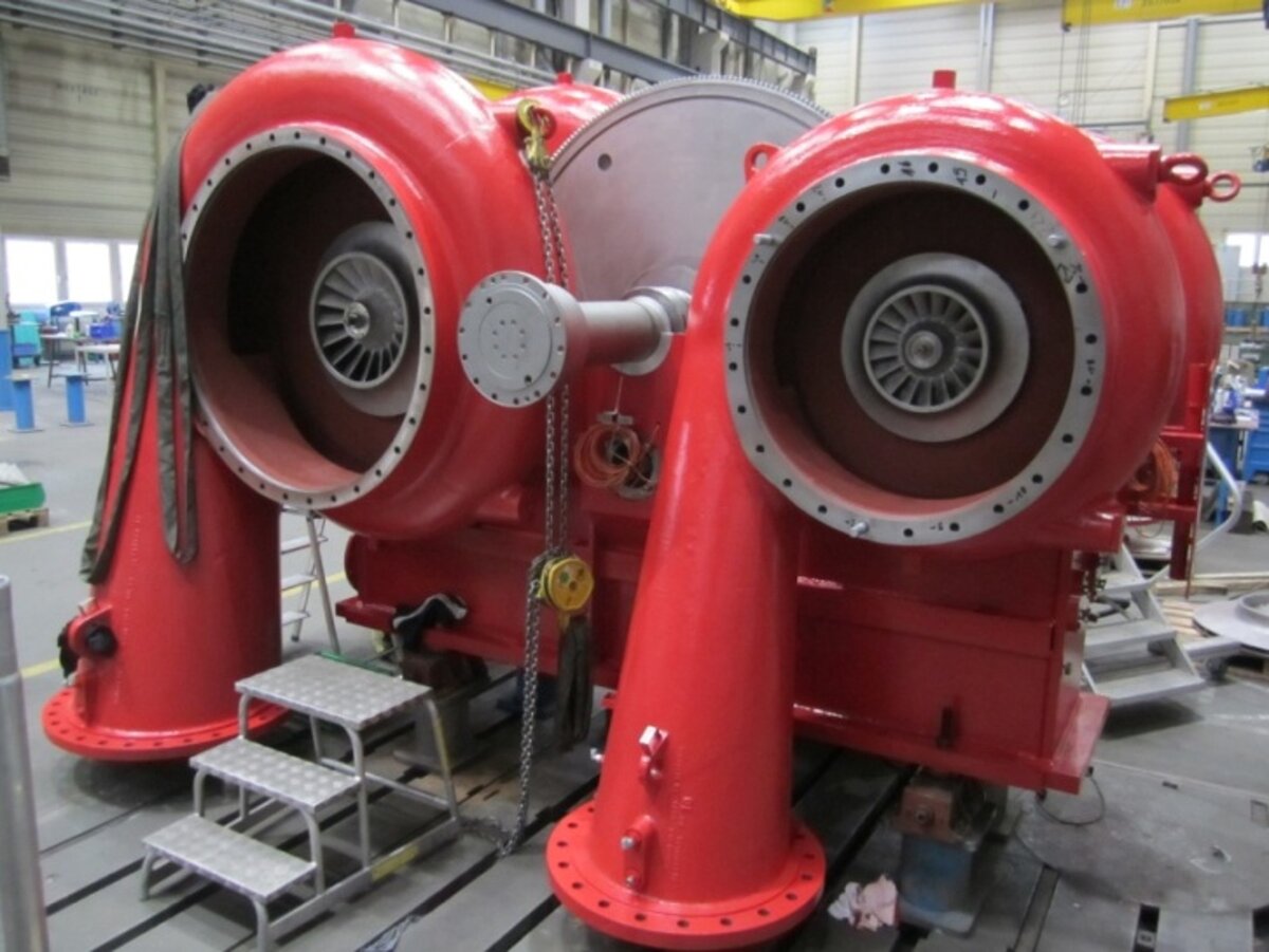 Große, rote Turbokompressor-Einheit mit zwei sichtbaren Rotoren in einer industriellen Werkstatt.