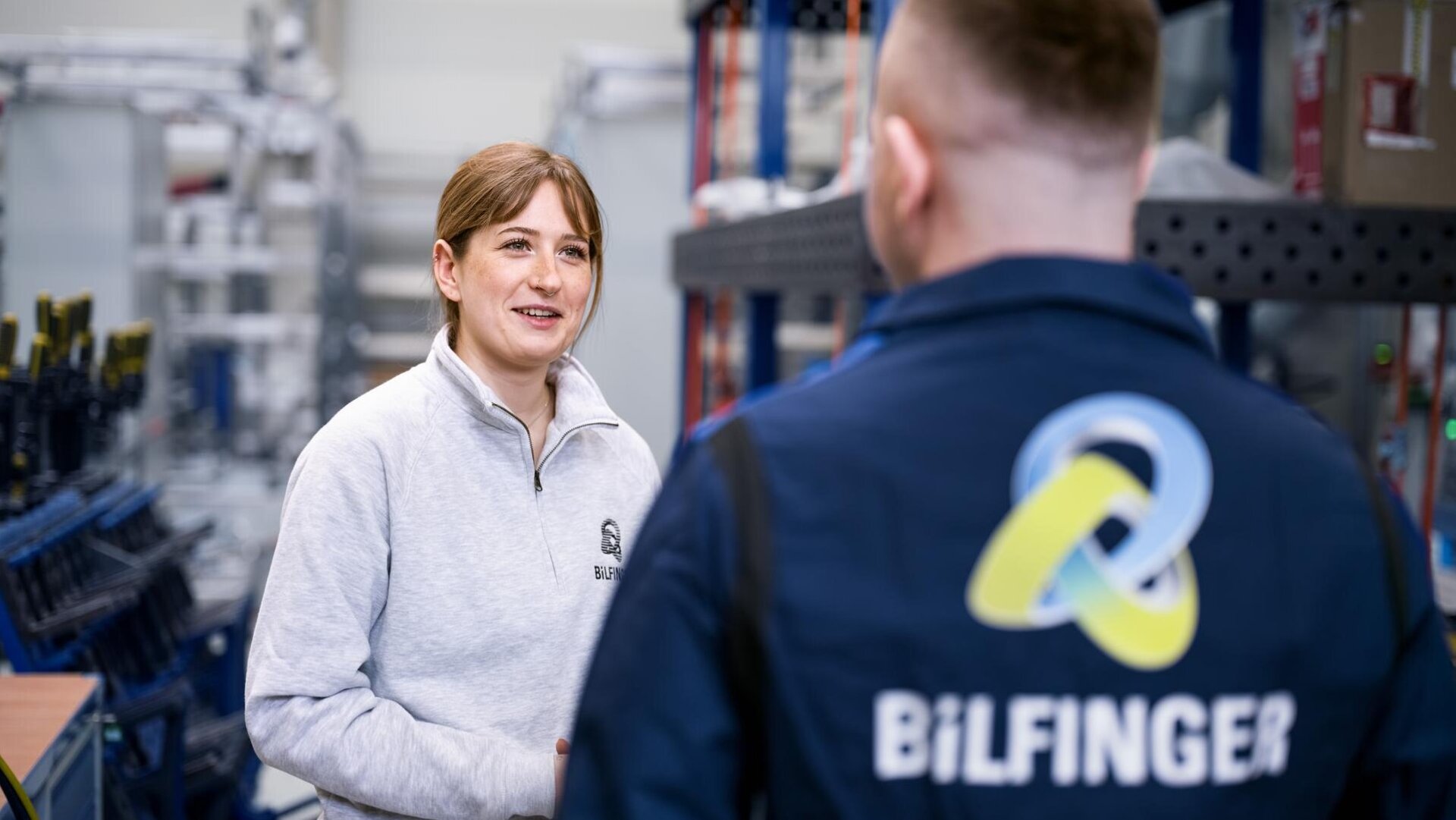 Two employees are standing in a workshop and talking.