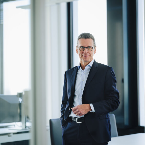 This image portrays Matti Jaekel, Bilfinger Group CFO, in a formal business suit standing confidently in a modern office setting