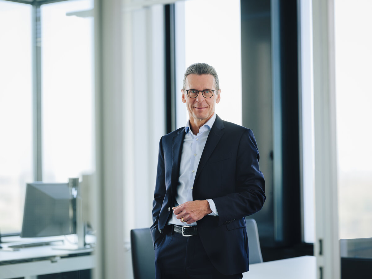 This image portrays Matti Jaekel, Bilfinger Group CFO, in a formal business suit standing confidently in a modern office setting