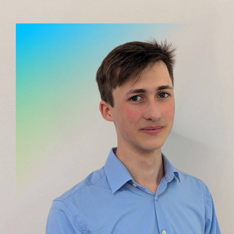 This image is a professional portrait featuring a person wearing a light blue collared shirt against a gradient background of blue and green, emphasizing a formal and polished appearance.