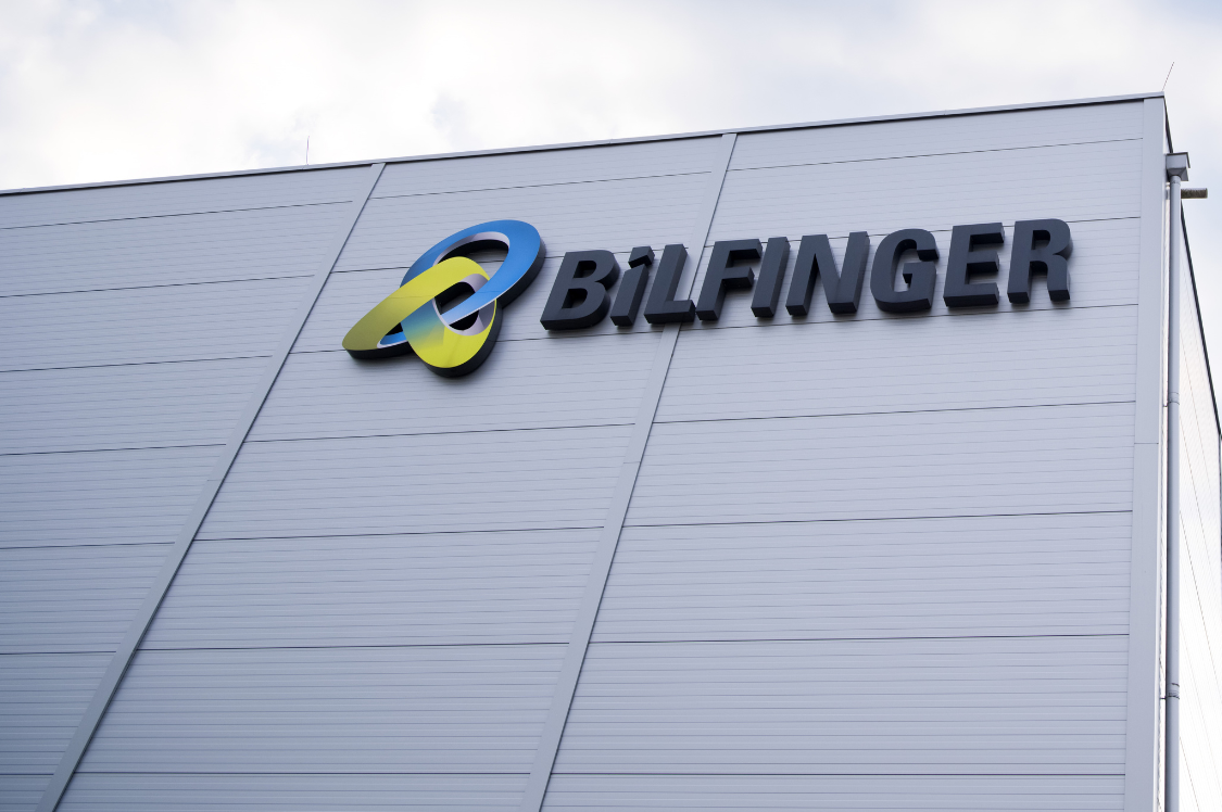 This image is a photograph of a building exterior prominently displaying the Bilfinger logo, emphasizing the company's branding and presence. The clear sky in the background adds a sense of openness and professionalism to the scene.