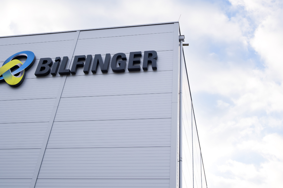 This image is a photograph of a building exterior prominently displaying the Bilfinger logo, emphasizing the company's branding and presence. The clear sky in the background adds a sense of openness and professionalism to the scene.