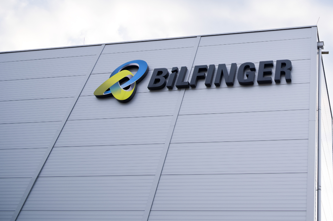 This image is a photograph of a building exterior prominently displaying the Bilfinger logo, emphasizing the company's branding and presence. The clear sky in the background adds a sense of openness and professionalism to the scene.